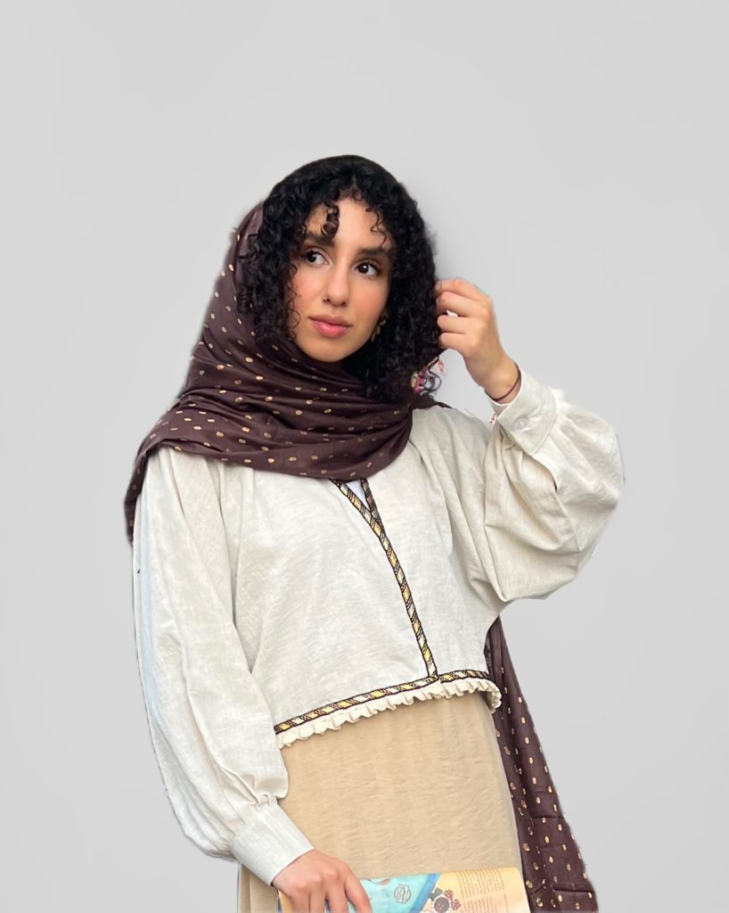 مدل زن با دامن کرم و کتسفید که یک لیسی قهوه ای خوسدوزی شده را به عنوان رویه کژوال استایل کرده است.